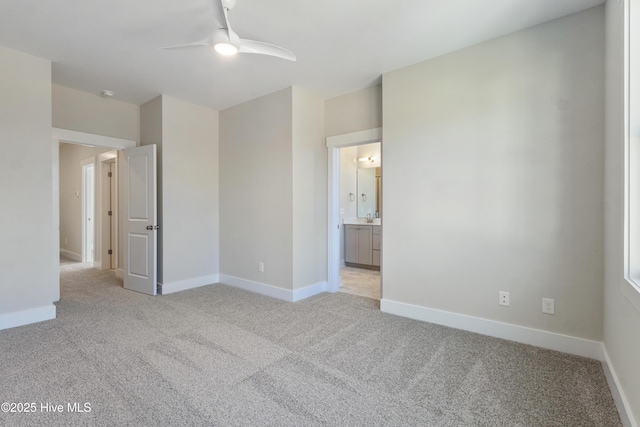 unfurnished bedroom featuring connected bathroom, light carpet, and ceiling fan