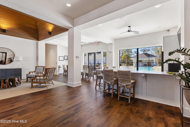 kitchen with dark wood-type flooring, a breakfast bar area, ceiling fan, and kitchen peninsula