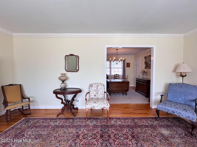 living area featuring crown molding, wood-type flooring, and a notable chandelier