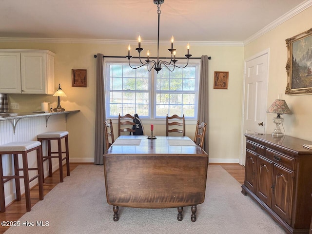 dining room with ornamental molding, a chandelier, and light hardwood / wood-style floors