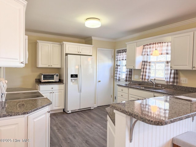 kitchen featuring stove, sink, white refrigerator with ice dispenser, and white cabinets