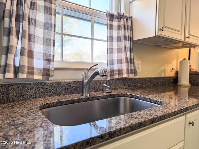 kitchen featuring white cabinetry, sink, and dark stone countertops