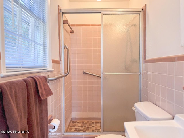 bathroom with a shower with door and tile walls