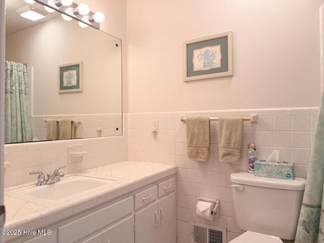 bathroom featuring vanity, toilet, and tile walls