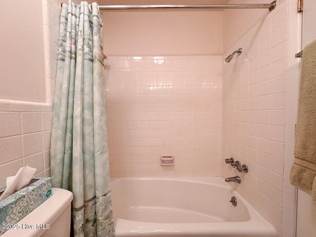 bathroom with tile walls and shower / bath combo with shower curtain