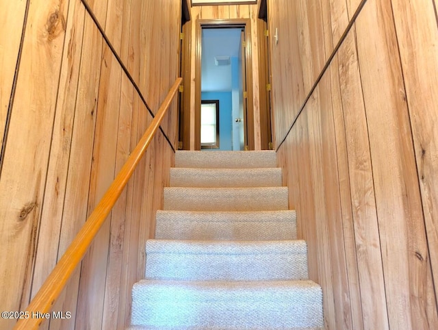 staircase with a barn door and wood walls