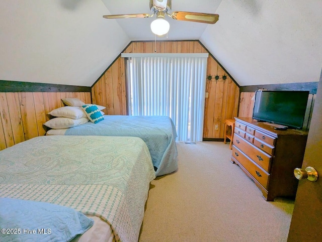 bedroom featuring vaulted ceiling, light colored carpet, ceiling fan, and wooden walls