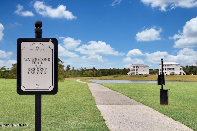 surrounding community with a water view and a lawn