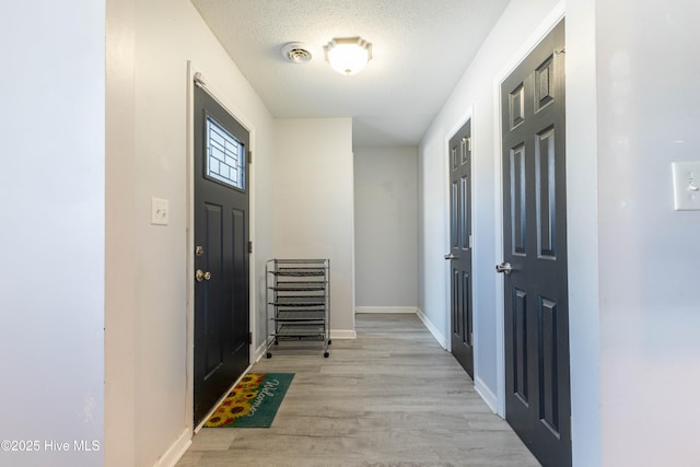 entryway with light hardwood / wood-style floors and a textured ceiling