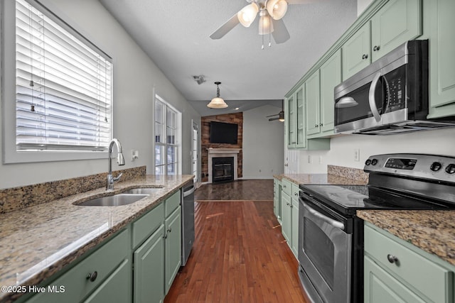 kitchen with sink, a textured ceiling, dark hardwood / wood-style flooring, green cabinets, and stainless steel appliances