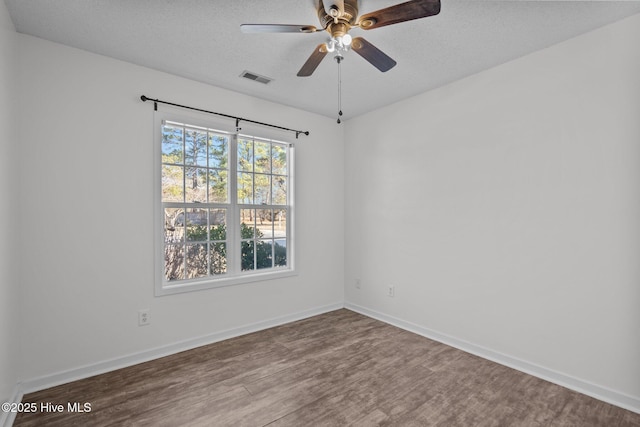 empty room with ceiling fan, wood-type flooring, and a textured ceiling