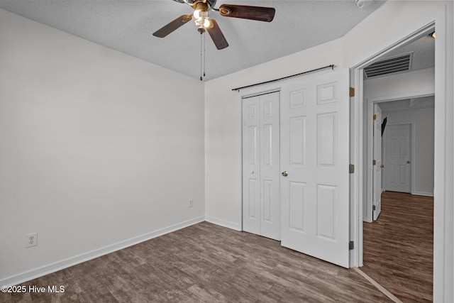 unfurnished bedroom with ceiling fan, hardwood / wood-style floors, a textured ceiling, and a closet