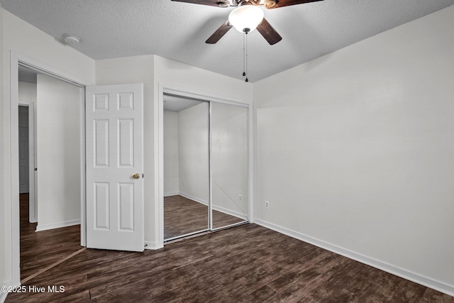 unfurnished bedroom featuring ceiling fan, dark wood-type flooring, a closet, and a textured ceiling