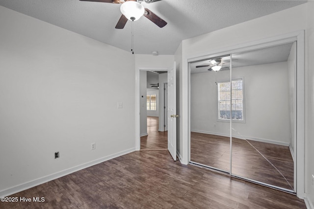 unfurnished bedroom featuring ceiling fan, dark wood-type flooring, a closet, and a textured ceiling