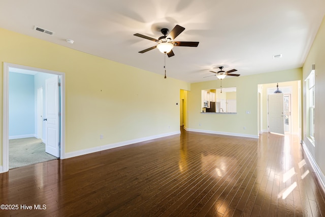 unfurnished living room featuring dark wood-type flooring and ceiling fan