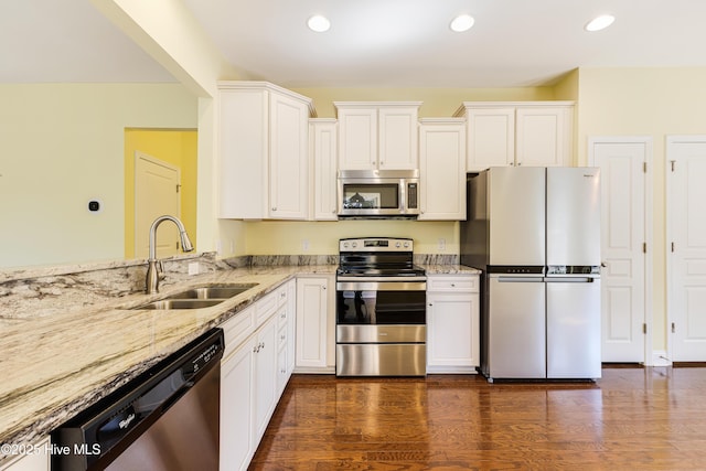 kitchen with white cabinetry, stainless steel appliances, light stone countertops, and sink