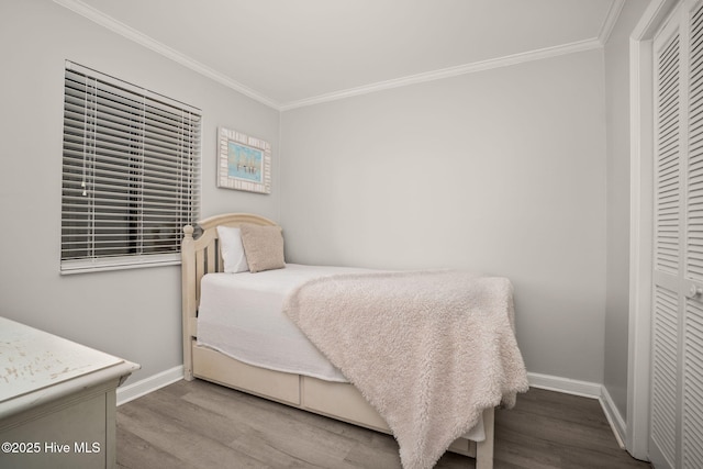 bedroom with ornamental molding, a closet, wood finished floors, and baseboards