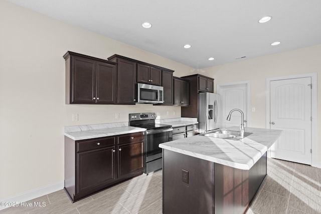 kitchen with stainless steel appliances, dark brown cabinets, a kitchen island with sink, and sink