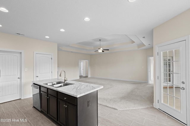 kitchen featuring sink, stainless steel dishwasher, a raised ceiling, an island with sink, and ceiling fan