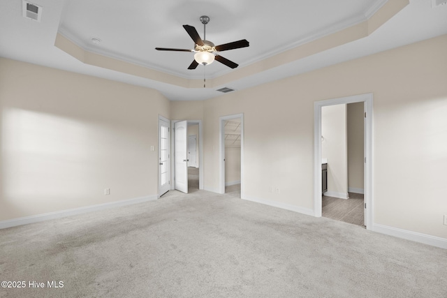 unfurnished bedroom with light colored carpet, ornamental molding, and a raised ceiling