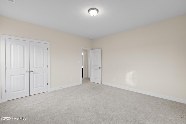 unfurnished bedroom featuring light colored carpet and a closet