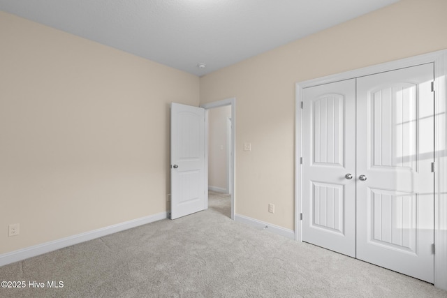 unfurnished bedroom featuring light colored carpet and a closet