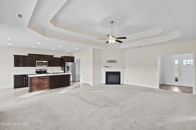 unfurnished living room with sink, ornamental molding, and a raised ceiling