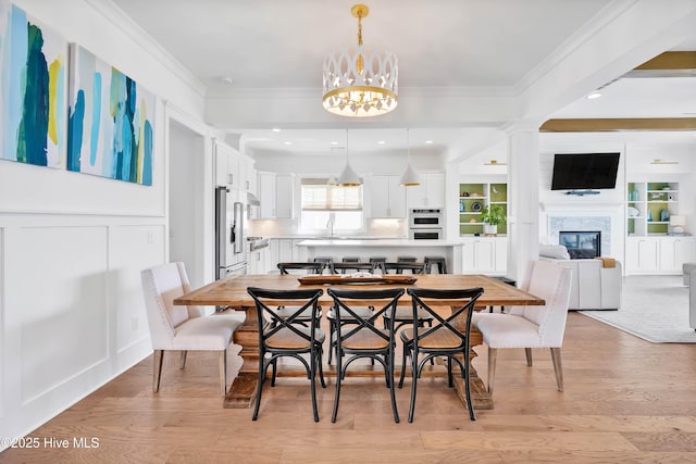 740 Waterstone Dr, Wilmington, NC 28411 - dining area featuring a chandelier, light wood finished floors, a glass covered fireplace, ornamental molding, and recessed lighting
