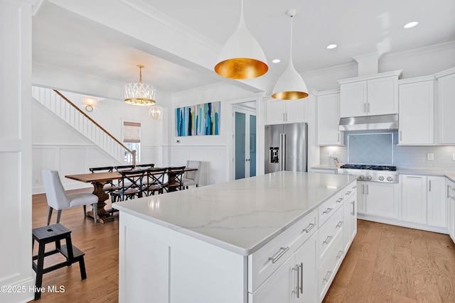 740 Waterstone Dr, Wilmington, NC 28411 - kitchen with appliances with stainless steel finishes, ornamental molding, a kitchen island, tasteful backsplash, and light wood-type flooring