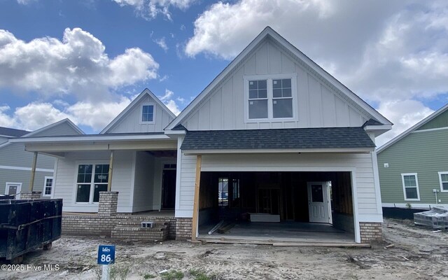 3377 Island Lakes Dr, Oak Island, NC 28461 - view of front of home with board and batten siding, a shingled roof, a porch, and a garage