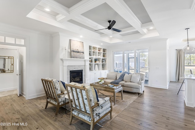 3377 Island Lakes Dr, Oak Island, NC 28461 - living area featuring crown molding, ceiling fan, baseboards, a glass covered fireplace, and coffered ceiling