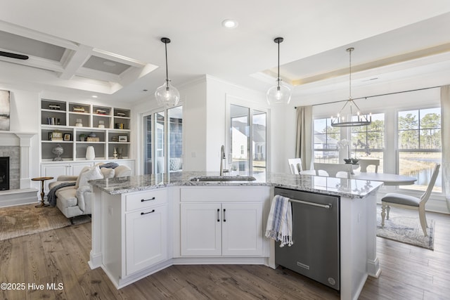 kitchen featuring a sink, ornamental molding, open floor plan, stainless steel dishwasher, and light stone countertops