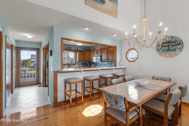 dining space featuring light wood-style flooring, a toaster, and a notable chandelier