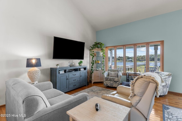 living area with high vaulted ceiling, wood finished floors, and baseboards