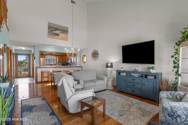 living room with a chandelier, a towering ceiling, and wood finished floors