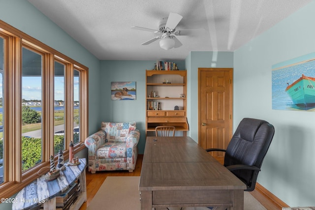 home office featuring plenty of natural light, a textured ceiling, ceiling fan, and wood finished floors