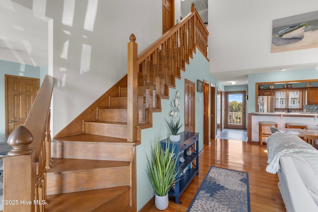 stairs featuring a high ceiling and wood finished floors