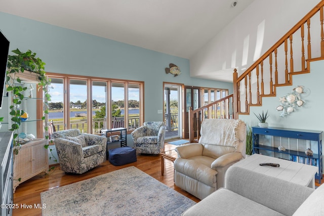 living area featuring high vaulted ceiling, radiator heating unit, stairway, and wood finished floors