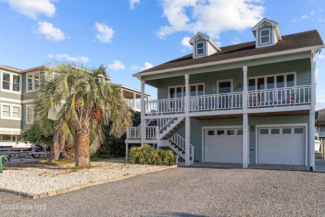 beach home with a porch, driveway, an attached garage, and stairs