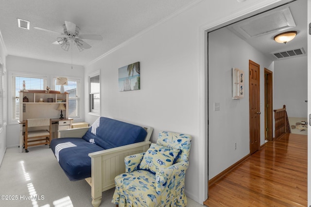 living area featuring visible vents, crown molding, light wood-style flooring, and baseboards