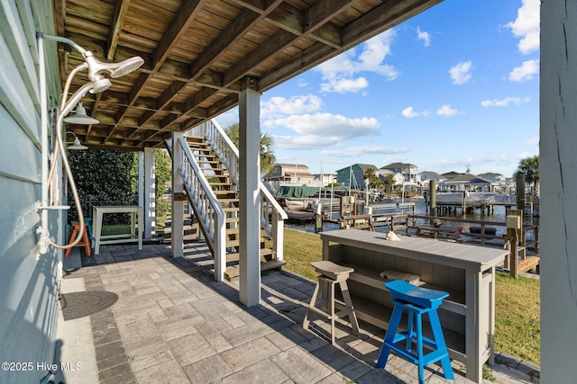 view of patio / terrace featuring a residential view, stairway, outdoor dry bar, a dock, and a water view