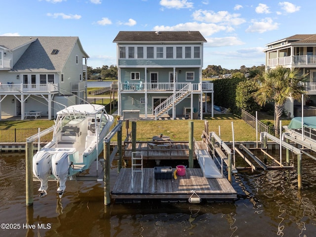 view of dock featuring a water view, a yard, boat lift, and fence