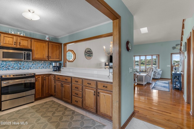 kitchen with crown molding, tasteful backsplash, light countertops, appliances with stainless steel finishes, and brown cabinetry