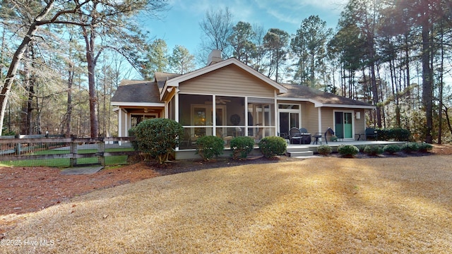 rear view of property with a sunroom and a lawn