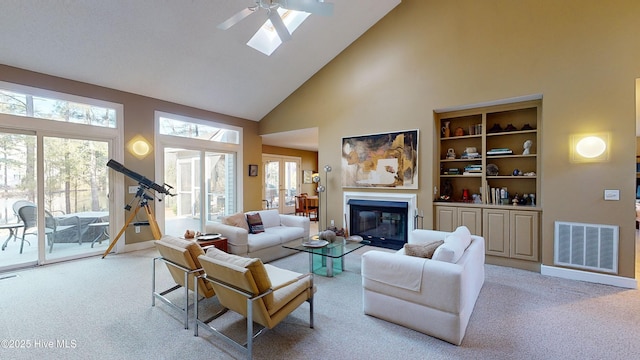 carpeted living room with ceiling fan, plenty of natural light, and high vaulted ceiling