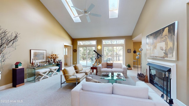 living room with ceiling fan, a skylight, high vaulted ceiling, and light carpet