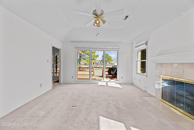 unfurnished living room featuring a tile fireplace, ceiling fan, a textured ceiling, vaulted ceiling, and light colored carpet