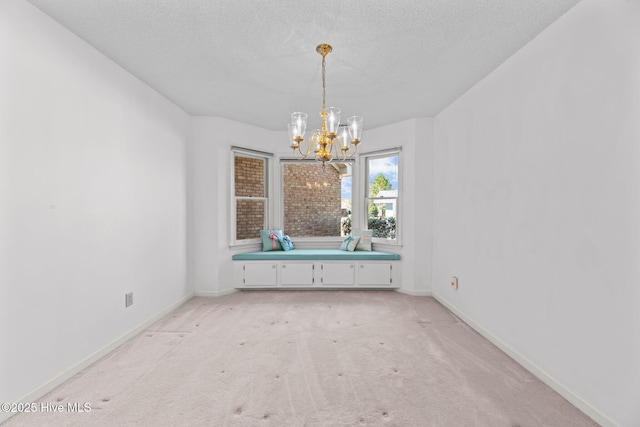 unfurnished dining area with an inviting chandelier, light colored carpet, and a textured ceiling