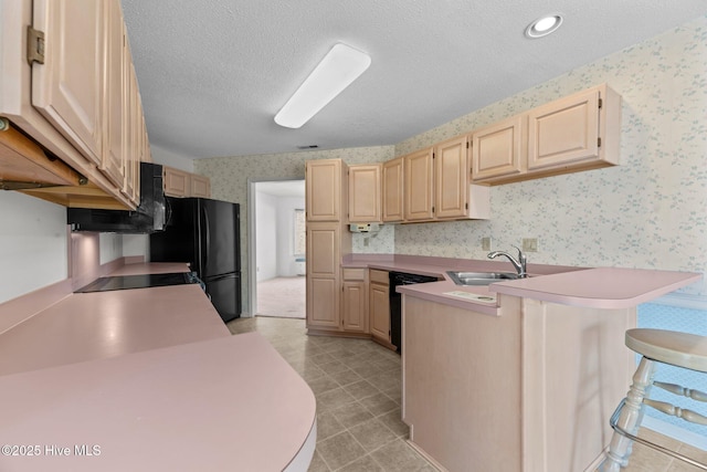 kitchen with a kitchen bar, sink, a textured ceiling, light brown cabinets, and kitchen peninsula