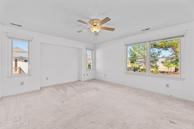 unfurnished room with light carpet, ceiling fan, and a textured ceiling